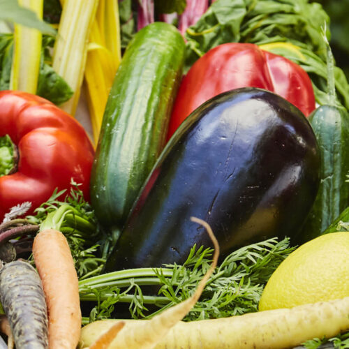 Eggplant and capsicum in a basket of other vegetables.